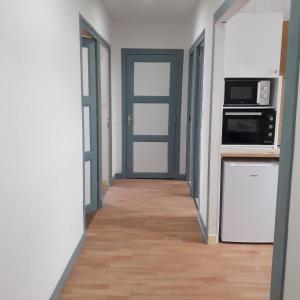 a hallway with a door leading to a kitchen with appliances at Appartement paisible - cœur de ville in Le Creusot