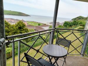 a table and chairs on a balcony with a view of the ocean at Sunnyside View Apartment -modern & cosy apartment with magnificent views to match in Youghal