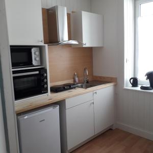 a kitchen with a counter with a microwave and a sink at Appartement paisible - cœur de ville in Le Creusot