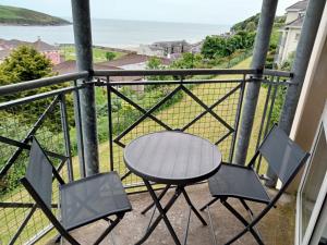 a table and chairs on a balcony with a view of the ocean at Sunnyside View Apartment -modern & cosy apartment with magnificent views to match in Youghal