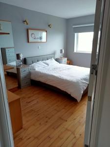 a bedroom with a white bed and a wooden floor at Sunnyside View Apartment -modern & cosy apartment with magnificent views to match in Youghal