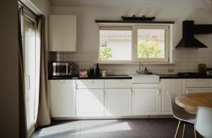 Una cocina con gabinetes blancos y una ventana. en Bungalow Rondomzon, en Putten
