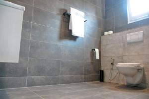 a bathroom with a toilet and a tiled wall at VOAK Home in Douala