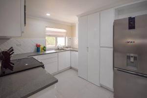 a kitchen with white cabinets and a stainless steel refrigerator at Blue Waters 25 5 bed apts in Bridgetown