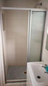 a white bathroom with a shower and a sink at Carol Close Upstairs - A spacious apartment with a view in Durbanville