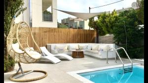 a patio with a couch and a chair next to a pool at Chris Rea Villa in Skiathos