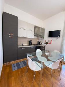 a kitchen with a glass table and white chairs at Sunny loft with terrace and Jacuzzi in the city centre in Palermo