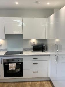 a kitchen with white cabinets and a microwave at Brand New Vintage 2 Bed Flat No Parties No Events in West Thurrock