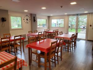 restauracja z czerwonymi stołami, krzesłami i oknami w obiekcie camping hôtel les airelles w mieście Saint-Cirgues-en-Montagne