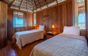 a bedroom with two beds and two windows at Jaguaribe Lodge e Kite in Fortim