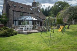 une maison avec une aire de jeux dans la cour dans l'établissement The Manor, à Little Dean