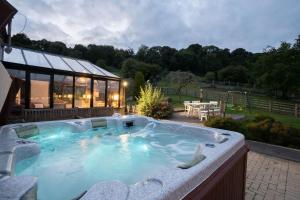 - un grand bain à remous dans une cour avec un bâtiment dans l'établissement The Manor, à Little Dean