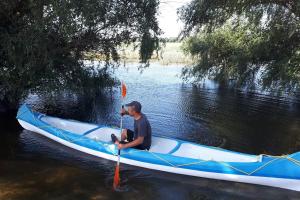 Un uomo è seduto in un kayak sull'acqua di Chilia 3 Apartments a Chilia Veche