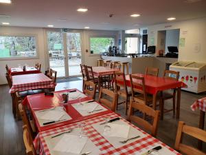 restauracja z czerwonymi stołami i krzesłami oraz kuchnia w obiekcie camping hôtel les airelles w mieście Saint-Cirgues-en-Montagne +33 zdjęcia