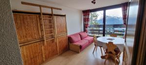salon z różową kanapą i stołem w obiekcie Studio la rosiere idéalement situé w mieście Montvalezan