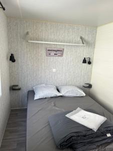 a bed with two pillows in a small room at Mobile home Grand Confort 30m² Modèle 1 in Arès