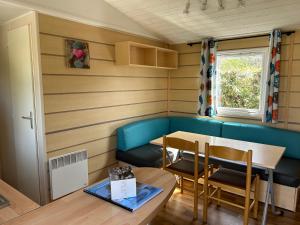 a dining room with a table and a blue couch at Mobile home Grand Confort 30m² Modèle 1 in Arès