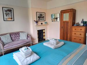 a living room with a large blue bed with towels at Muswell Hill B&B in London