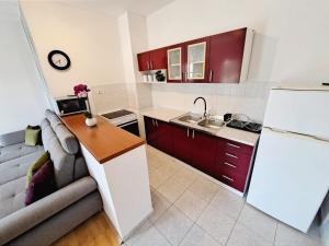 una cocina con armarios rojos y un sofá en una habitación en Apartman Lara, en Pašman