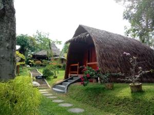 a small hut with a thatch roof and a pathway at Orangutan Bungalow in Bukit Lawang