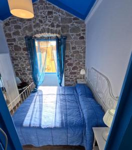 een slaapkamer met een blauw bed en een raam bij Sole Azzurro Suite in Bosa