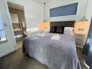 a bedroom with a bed with two towels on it at Gorgeous Lake Lodge with HTub Outstanding Views in Annan