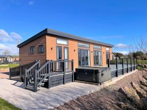 a tiny house with a porch and a deck at Gorgeous Lake Lodge with HTub Outstanding Views in Annan