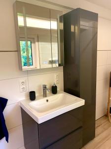 La salle de bains est pourvue d'un lavabo blanc et d'un miroir. dans l'établissement House of Happiness mit Seeblick, à Hungen