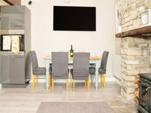 a dining room with a table with chairs and a tv at Acre Hill Cottage in Harrop Fold
