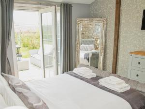 a bedroom with a bed with a mirror and a balcony at Acre Hill Cottage in Harrop Fold