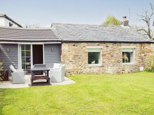 a stone house with a table and chairs in a yard at Acre Hill Cottage in Harrop Fold