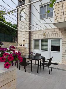 a patio with a black table and chairs and flowers at Apartment Deni in Solin