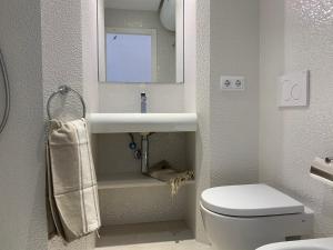ein Badezimmer mit einem WC, einem Waschbecken und einem Spiegel in der Unterkunft Copacabana 21 in Es Pujols