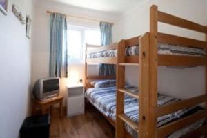 a bedroom with two bunk beds and a television at Summercliffe Chalet No 75 in Swansea