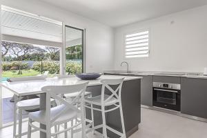 a kitchen with white chairs and a counter with a table at Villa BLUE in Saint-François