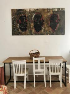 une table avec quatre chaises et un tableau sur le mur dans l'établissement Casa Dona Ana by Casa Dona Sol, à Olhão