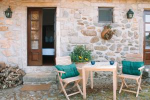 a table and chairs in front of a stone house at The Quixote House in Caminha