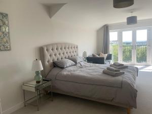 a bedroom with a large bed with a large window at Beautiful Executive Home in Llanelli