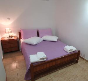 um quarto com uma cama com lençóis roxos e almofadas brancas em Ailamakis Apartements em Zákros