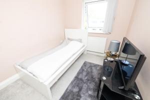 a white bedroom with a bed and a tv at Newly refurbished apartment in Elmers End
