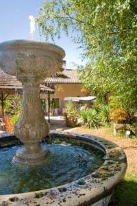 ein großer Brunnen in der Mitte eines Gartens in der Unterkunft Hostellerie Sarrasine - Mâcon Est in Replonges