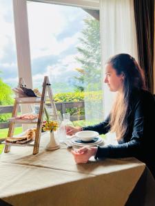 una mujer sentada en una mesa con una taza de café en La Roche Hotel Appartments, en Aosta