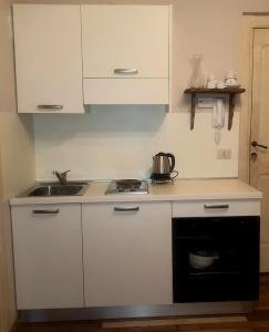 a kitchen with white cabinets and a sink and a stove at La Casaregina in Valdieri