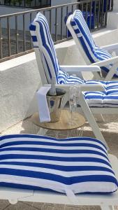 - deux chaises bleues et blanches et une table avec un verre de vin dans l'établissement Casa Lucia, à Caniles
