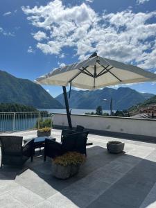 une terrasse avec un parasol, des chaises et une table dans l'établissement La Terrazza Sul Lago, à Ossuccio