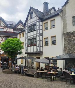 a building with tables and umbrellas in front of it at FeWo Innenstadt mit Dachterasse, Grill, bis 8 Personen, 3 SZ in Cochem