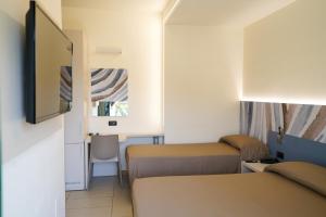 Habitación pequeña con 2 camas y espejo. en Hotel Taormina, en San Benedetto del Tronto