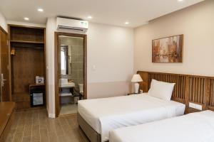 a hotel room with two beds and a bathroom at Palo Santo Hotel Phu Quoc in Phu Quoc