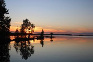a sunset over a lake with trees in the water at LevonMajat in Joensuu