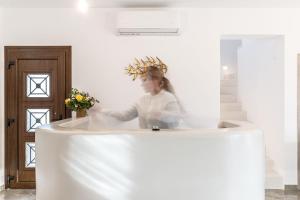 une femme debout derrière un comptoir blanc dans une pièce dans l'établissement Naxian Air, à Ágios Geórgios